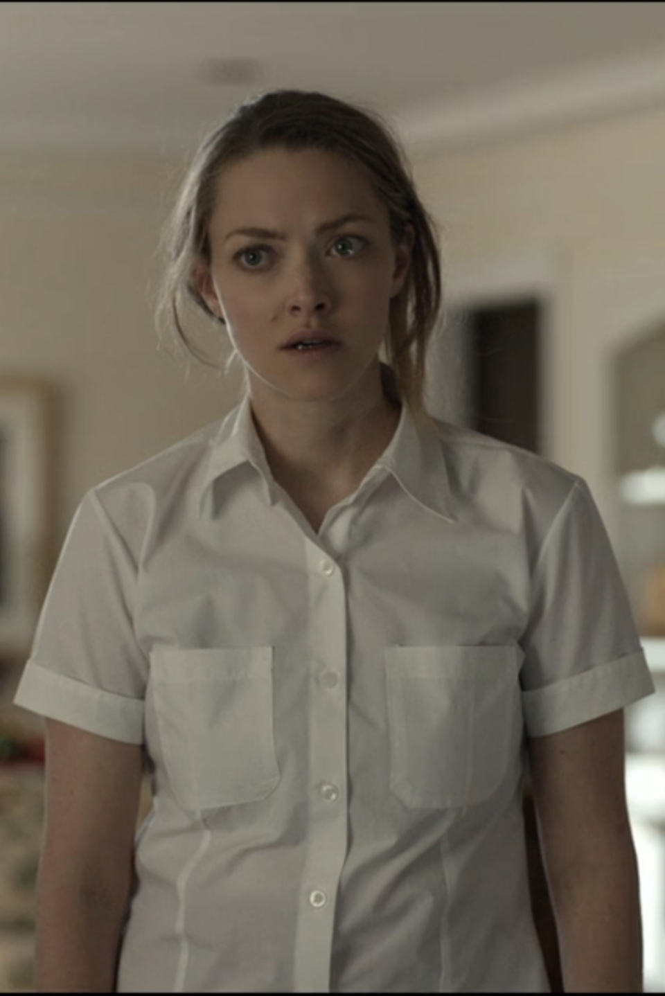 Elizabeth in a collared shirt looks surprised in a home setting