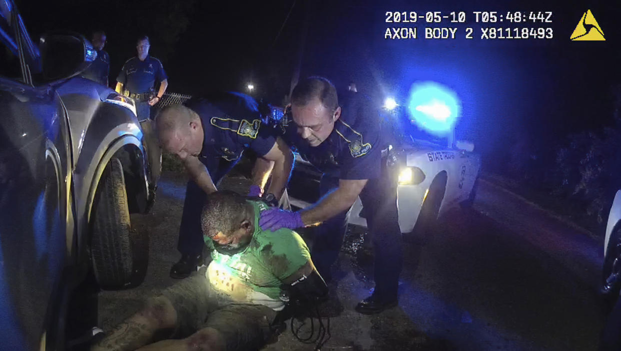 This image from the body camera of Louisiana State Police Trooper Dakota DeMoss shows his colleagues, Kory York, center left, and Chris Hollingsworth, center right, holding up Ronald Greene before paramedics arrived on May 10, 2019, outside of Monroe, La. (Louisiana State Police via AP)