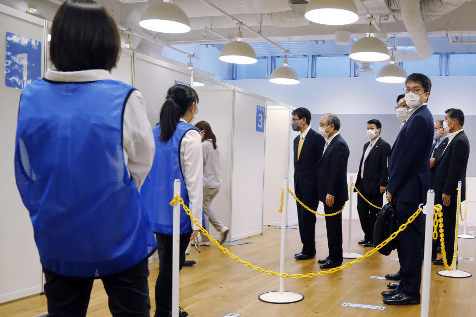 Covid 19 Vaccine Minister Taro Kono, center left, and Masayoshi Son, chief executive of technology company SoftBank Group Corp., center right, visit an inoculation site set up by Japanese technology company SoftBank Group Corp. at a WeWork office Tuesday, June 15, 2021, in Tokyo. Japanese companies have joined the effort to speed up the country’s lagging coronavirus vaccine rollout before the Tokyo Olympics begin next month. (AP Photo/Yuri Kageyama)