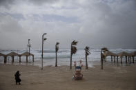 A woman walks on the beach next to a statue of the first Israeli Prime Minister David Ben Gurion, in Tel Aviv, Israel, Wednesday, Jan. 16, 2019. A harsh weather front brought sandstorms, hail and rain to parts of the Middle East, with visibility down in The Egyptian capital as an orange cloud of dust blocked out the sky. Dusty winds whipped through Israel and the West Bank as well on Wednesday, with hail falling near Tel Aviv and meteorologists announcing that snow was expected later in the day in Jerusalem. (AP Photo/Oded Balilty)