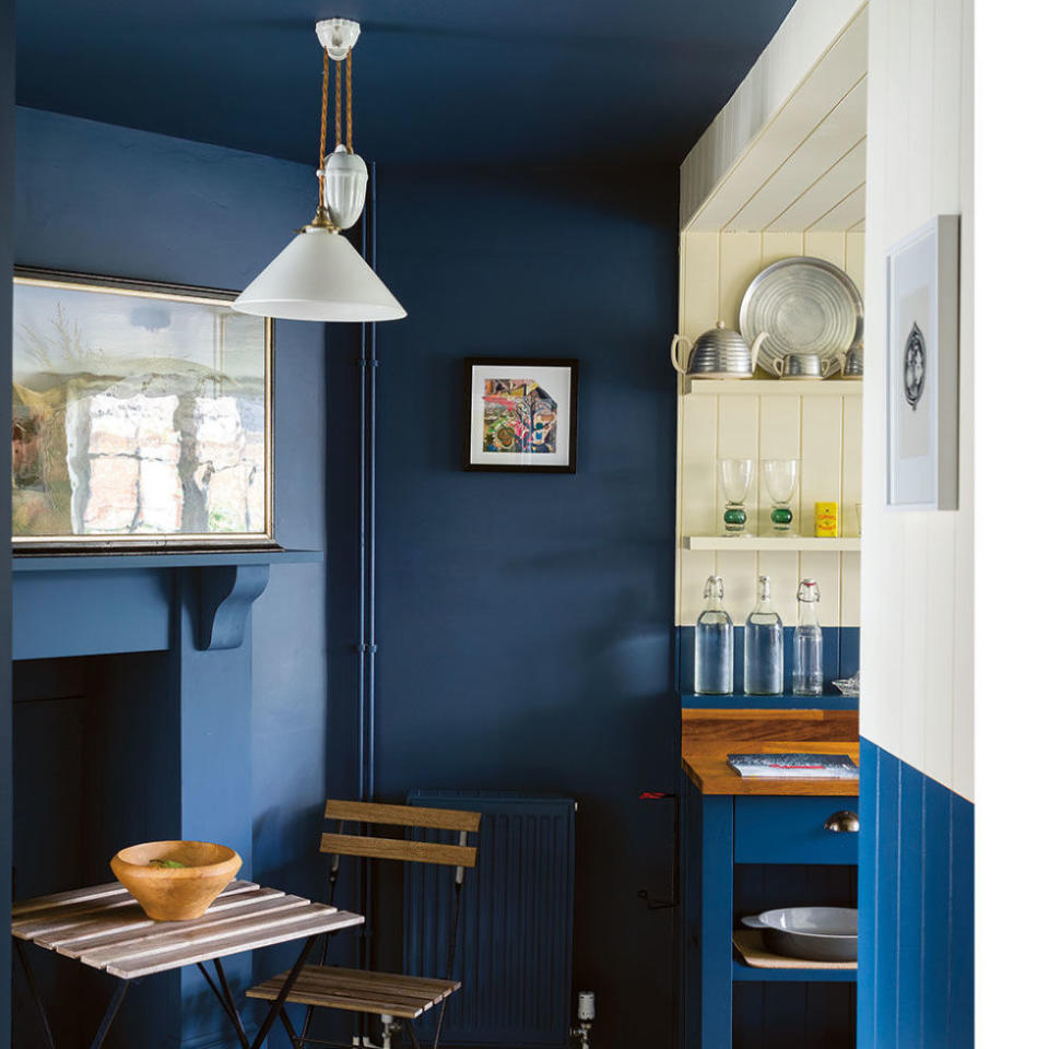 <p>More than the walls were painted blue here-check out the ceiling and the fireplace. "Using one color in a confined area makes it feel bigger," says Joa Studholme, author of Farrow & Ball's book <em><a rel="nofollow noopener" href="https://www.amazon.com/Farrow-Ball-How-Decorate/dp/1784720879?tag=syndication-20" target="_blank" data-ylk="slk:How to Decorate;elm:context_link;itc:0;sec:content-canvas" class="link ">How to Decorate</a></em>, who adds that if the mantel were white, it would dwarf the room. Another reason to go monochromatic? It helps mask not-so-pretty stuff like exposed pipes or a radiator (use a forgiving eggshell finish). The half-painted walls mark the transition into the kitchen and break up all that navy.</p><p><strong>RELATED: <a rel="nofollow noopener" href="http://www.redbookmag.com/home/decor/g4538/cheap-home-makeover/" target="_blank" data-ylk="slk:How to Do a Home Makeover Without Breaking the Bank;elm:context_link;itc:0;sec:content-canvas" class="link ">How to Do a Home Makeover Without Breaking the Bank</a></strong><br></p>
