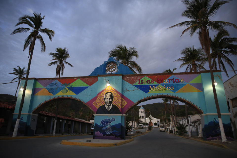 A mural of Nelson Mandela, who spent many of his imprisoned years in an island prison in South Africa, adorns a gate in front of the dock where prison staff and inmates arrive in Navy boats to the now closed Islas Maria penal colony located off Mexico's Pacific coast, at dawn Sunday, March 17, 2019. Islas Marias was the last of its kind, the final of a half dozen island penal colonies that were scattered around Latin America. (AP Photo/Rebecca Blackwell)