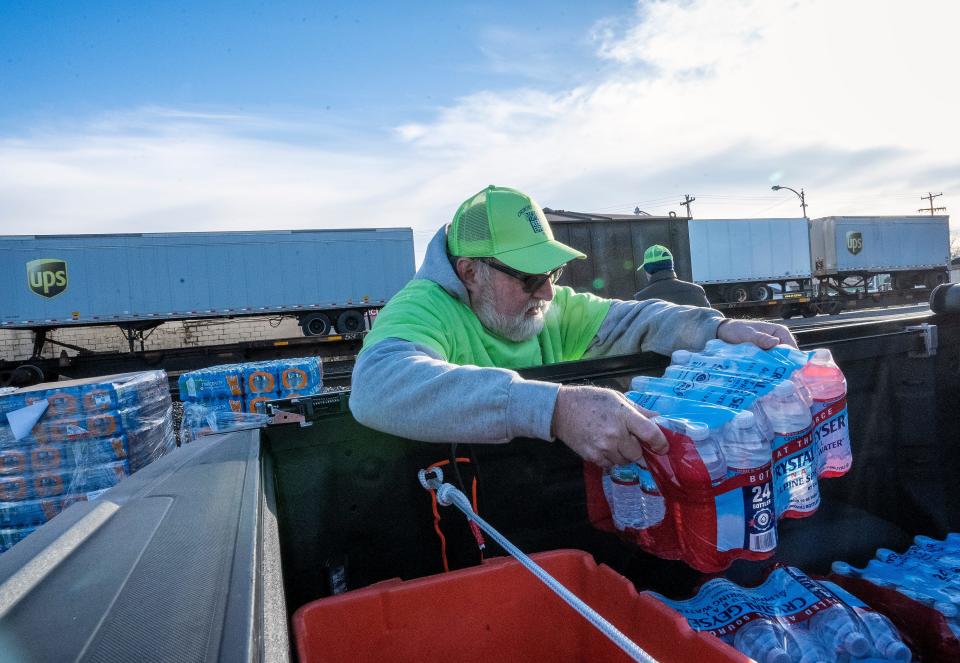 Feb 21, 2023; East Palestine, Ohio, USA;  Larry Cohen who was volunteering with the Church of Christ group loads donated water into a truck at a drive through area where local residents can get fresh water. Mandatory Credit: Brooke LaValley/Columbus Dispatch