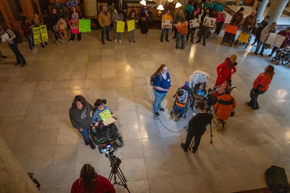 Anastasia Davis and her 15-year-old son Alexander Davis (bottom left), talk with a reporter on Monday, Jan. 22, 2024, at the Indiana Statehouse. About 100 people showed up for a rally who are at odds with a recent Family and Social Services Administration decision to eliminate financial reimbursement for family members who care for severely disabled and medically complex children.