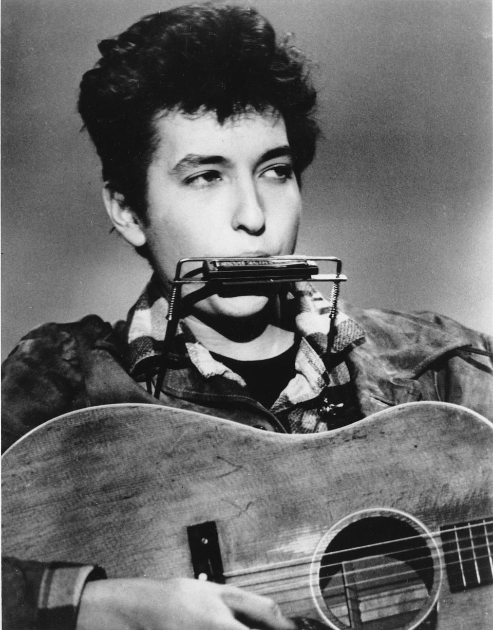 Folk singer and songwriter Bob Dylan plays the harmonica and acoustic guitar in March 1963 at an unknown location.