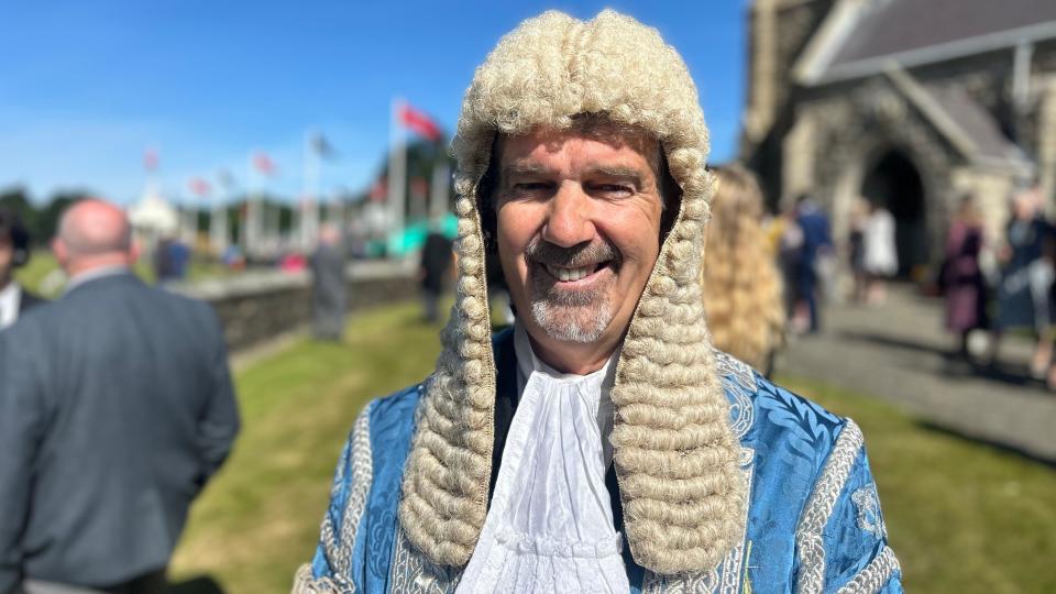 A smiling man wearing a long ceremonial white wig and blue robes (Laurence Skelly)