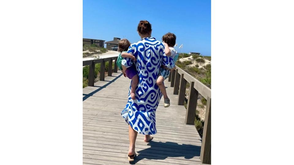 Princess Eugenie in a white and blue dress carrying two young boys