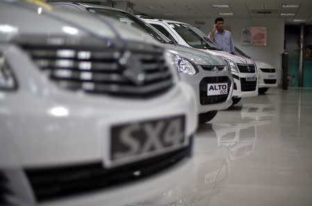 A sales executive speaks on his mobile phone as he stands in between Maruti Suzuki cars inside a showroom in New Delhi