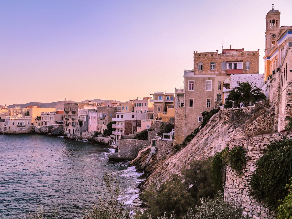 building along the coast of syros greece at sunset