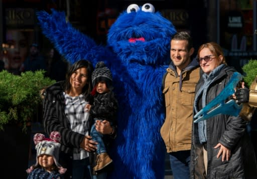 A person dressed as "Sesame Street" character Cookie Monster poses for a photo with tourists on 42nd Street
