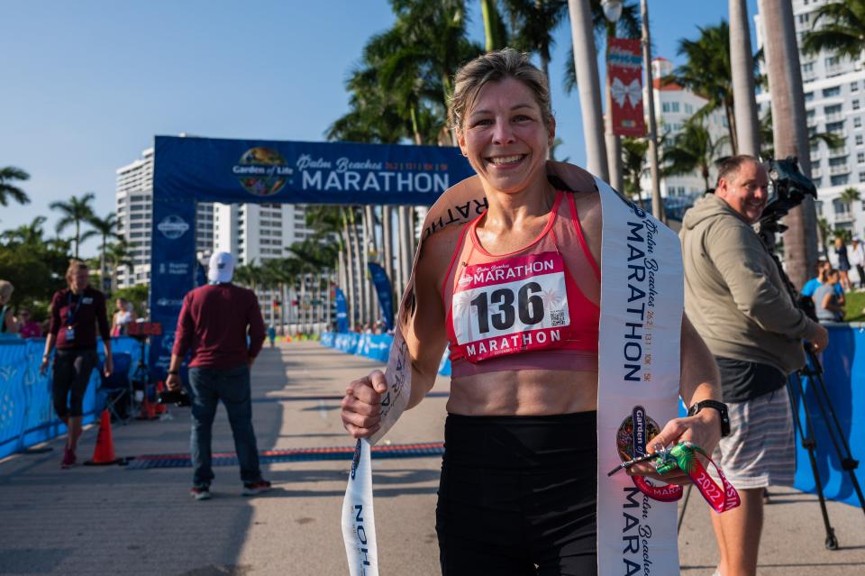 Women's overall race winner Marilene Gosselin, of Quebec, Canada, poses for a picture with her race completion medal and the finish line ribbon on South Flagler Drive during the Garden of Life Palm Beaches Marathon on Sunday, December 11, 2022, in downtown West Palm Beach, FL. Thousands of runners participated in races held over the weekend, which ranged from a 5K all the way to a 26.2 mile-long marathon.