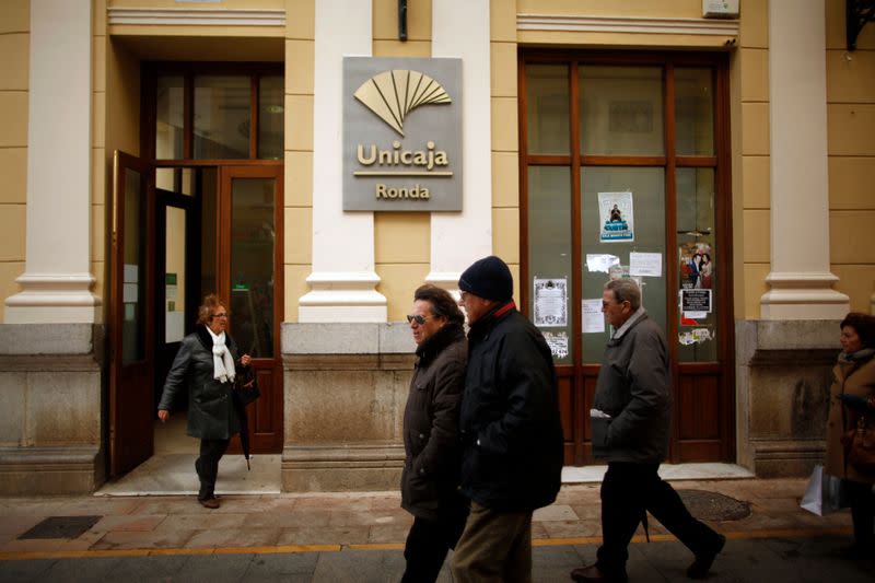 FILE PHOTO: People walk past a Unicaja bank branch at La Bola street in downtown Ronda