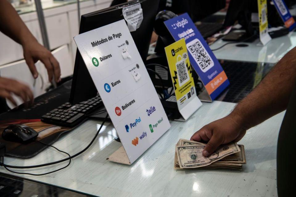 Una persona pagando con dólares en un comercio en Venezuela.