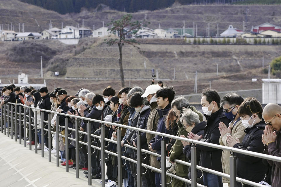 People observe a moment of silence at 2:46 p.m., the moment the earthquake struck in Rikuzentakata, Iwate prefecture, northern Japan Monday, March 11, 2024. Japan marked the 13th anniversary of the massive earthquake, tsunami and nuclear disaster. (Kyodo News via AP)