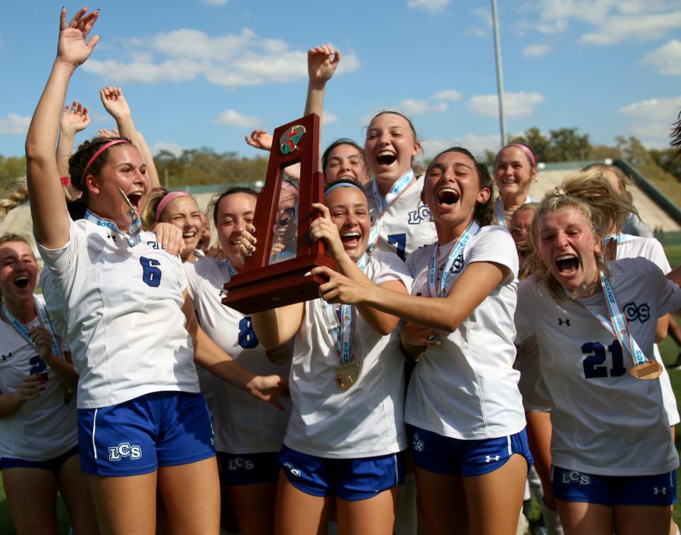 Lakeland Christian senior Lily Harrington holds up the state championship trophy as she celebrates with her teammates, including Gretchen Caswell (6), Emily Smith (8), Kaelyn Diaz (behind Harrington), Ava Wood (7), Maddie Lopez (11) and KJ Straub (21). LCS defeated St. Johns Country Day, 2-1, in the Class 2A state championship game.