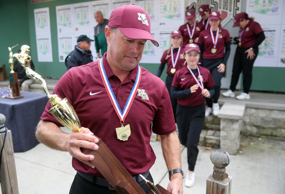 11. New Albany girls golf coach Rich Ritter exits the awards stage with his team while carrying the Division I state championship trophy after the Eagles captured their fourth title in a row Oct. 23 at Ohio State's Gray Course.