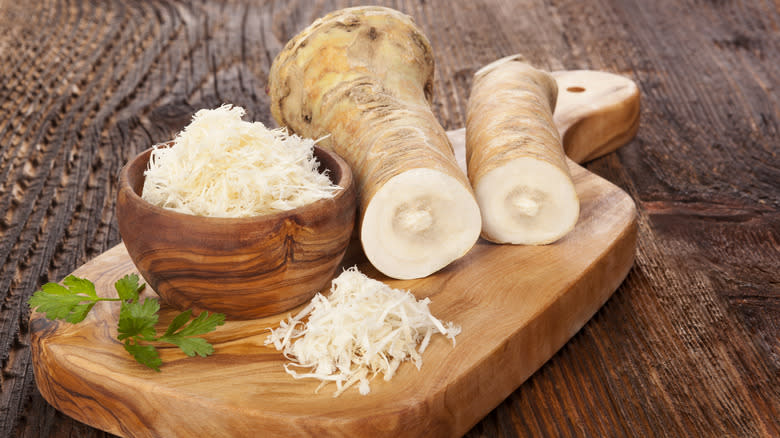 Grated horseradish on wooden board 