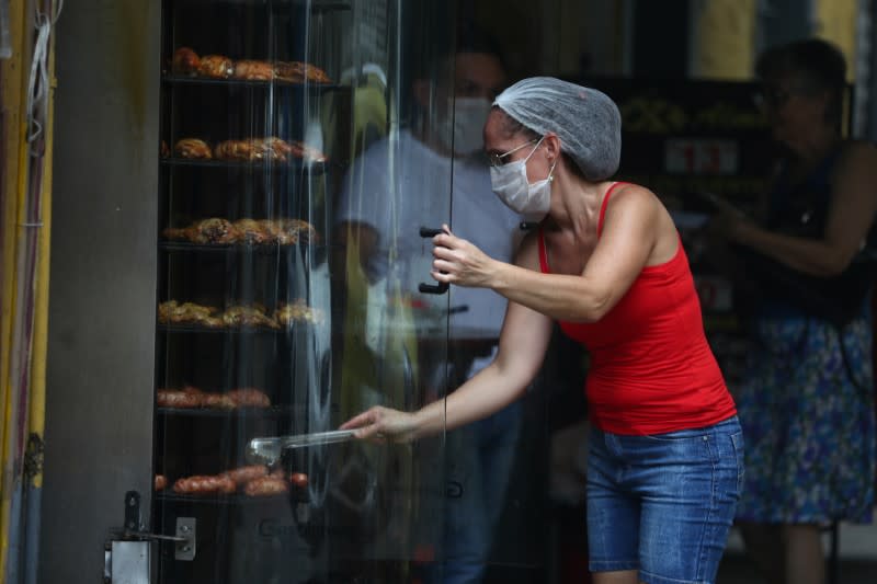 A worker displays pieces of chicken wearing a protective mask, amid coronavirus fears, at a restaurant in Rio de Janeiro