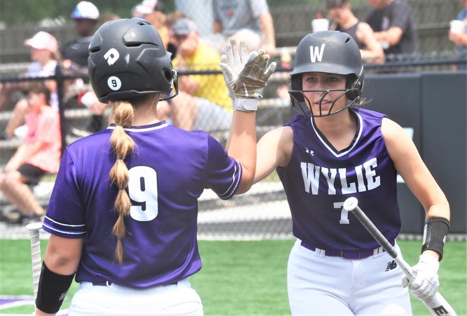 Wylie's Kynslee George, right, is congratulated by Ryleigh Whitehead after scoring the game's first run in the first inning against Aledo.