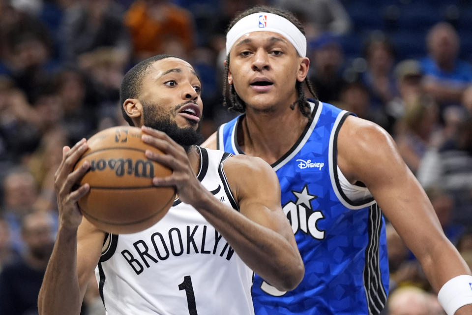 Brooklyn Nets forward Mikal Bridges, left, looks to pass the ball as Orlando Magic forward Paolo Banchero defends during the first half of an NBA basketball game,\ Wednesday, March 13, 2024, in Orlando, Fla. (AP Photo/John Raoux)