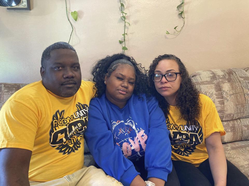 McKynzi Douglas, center, sits with her parents, John and Janay Douglas, inside their home on Thursday, Jan. 26, 2023, in St. Louis, Mo. McKynzi and other students of Central Visual and Performing Arts High School in St. Louis recently returned to school for the first time since fleeing from a shooting last October that killed two and wounded seven. (AP Photo/Jim Salter)