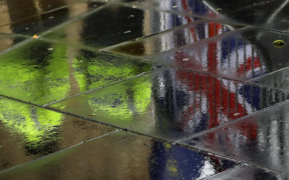 Police officers are reflected in a wet pavement as they walk past flags tied to railings by anti-Brexit demonstrators outside parliament in London, Thursday, Jan. 24, 2019. The European Union's chief Brexit negotiator, Michel Barnier, is rejecting the possibility of putting a time limit on the "backstop" option for the Irish border, saying it would defeat the purpose. (AP Photo/Kirsty Wigglesworth)