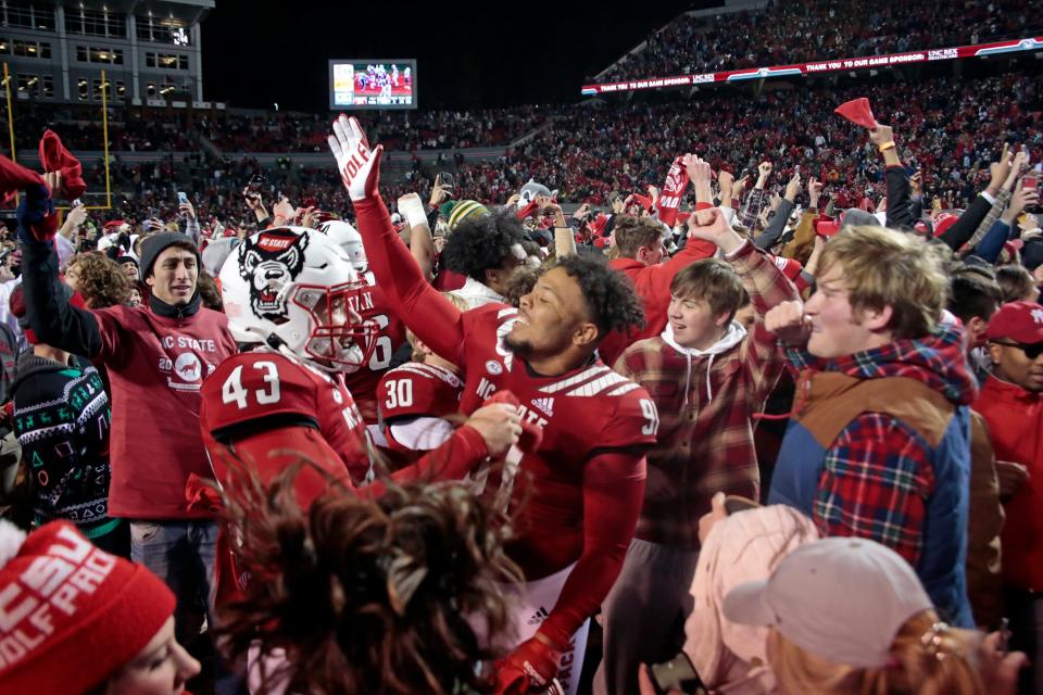 North Carolina State fans mingle on the field with players after the team's win over rival North Carolina in an NCAA college football game Friday, Nov. 26, 2021, in Raleigh, N.C. (AP Photo/Chris Seward)