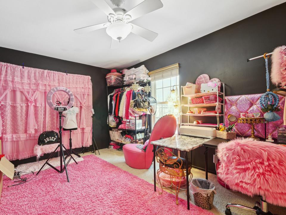 A room with a ring light, pink backdrop, and a mannequin torso.