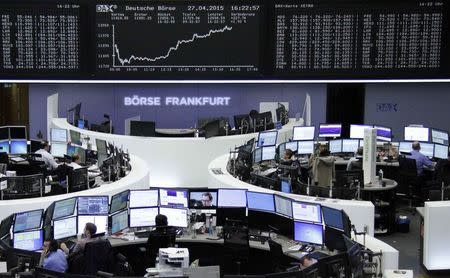 Traders are pictured at their desks in front of the DAX board at the Frankfurt stock exchange April 27, 2015. REUTERS/Remote/Staff