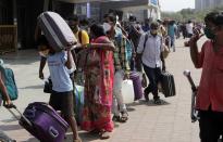 People wearing masks as a precaution against the coronavirus stand in a queue to board trains at Lokmanya Tilak Terminus in Mumbai, India, Friday, April 16, 2021. Migrant workers are swarming rail stations in India's financial capital Mumbai to go to their home villages as virus-control measures dry up work in the hard-hit region. The government of Maharashtra state imposed lockdown-like curbs on Wednesday for 15 days to check the spread of the virus. It closed most industries, businesses and public places and limited the movement of people, but didn’t stop the bus, train and air services. An exodus ensued, with panicked day laborers hauling backpacks onto overcrowded trains leaving Mumbai, travel that raises fears of infections spreading in rural areas. (AP Photo/Rajanish Kakade)