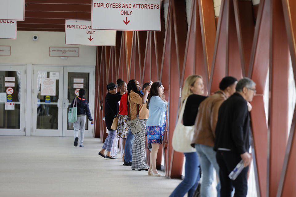 People leaving the Broward County Courthouse stop to look at part of a crane that dropped onto the Southeast Third Avenue bridge over the New River in downtown Fort Lauderdale, Fla., Thursday afternoon, April 4, 2024. (Carline Jean/South Florida Sun-Sentinel via AP)