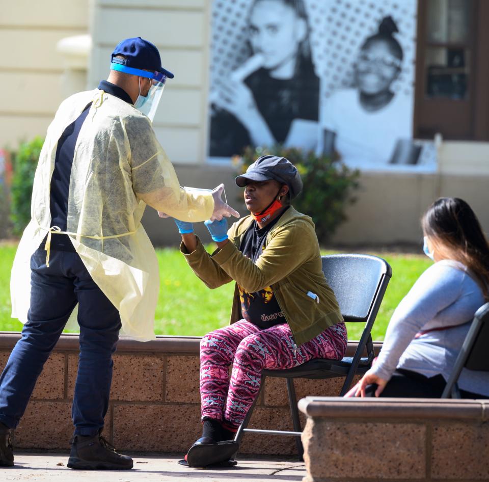 A local resident is given a face mask as she waits to be tested for COVID-19 at a mobile testing station in Compton, Calif., on April 28, 2020. St. John's Well Child and Family Center provided COVID-19 testing sites in African-American and Latino communities which have been neglected in terms of testing as compared to wealthier areas of Los Angeles County. (Photo by Robyn Beck / AFP) (Photo by ROBYN BECK/AFP via Getty Images)