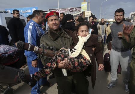 A member of the Palestinian security forces carries a girl, who needs to receive medical treatment outside Gaza, as she waits to cross into Egypt at the Rafah crossing between Egypt and the southern Gaza Strip December 21, 2014. REUTERS/Ibraheem Abu Mustafa