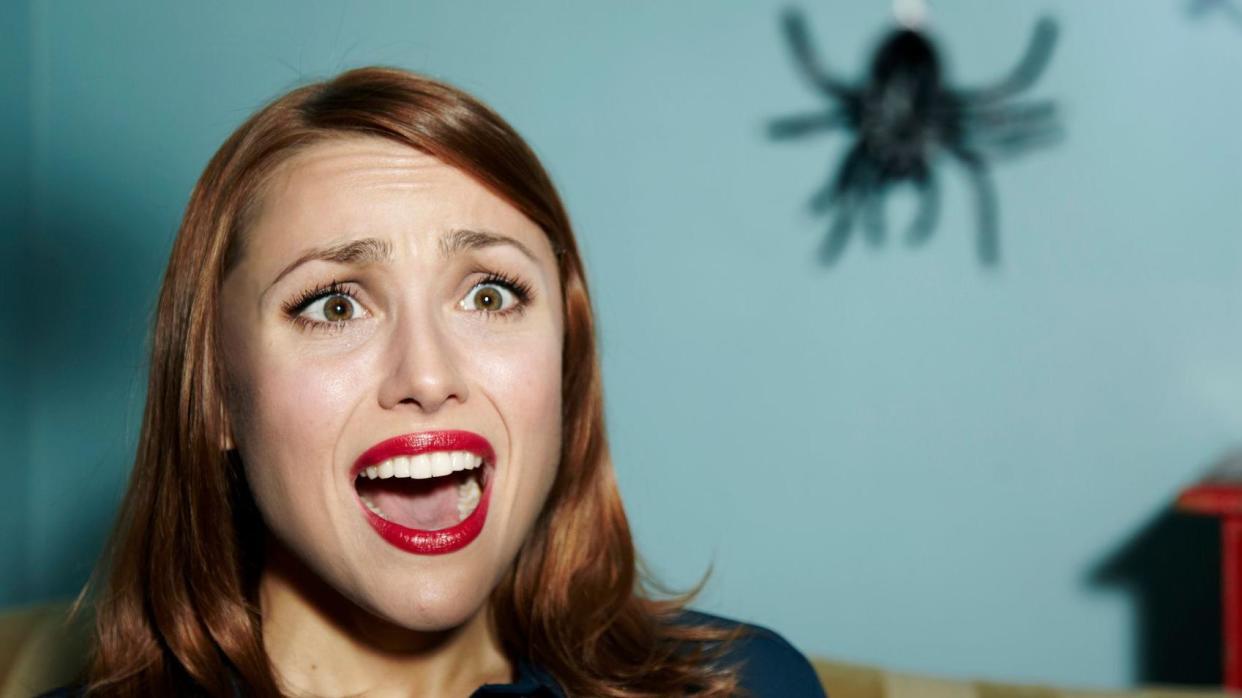 Una mujer grita al ver una araña. 