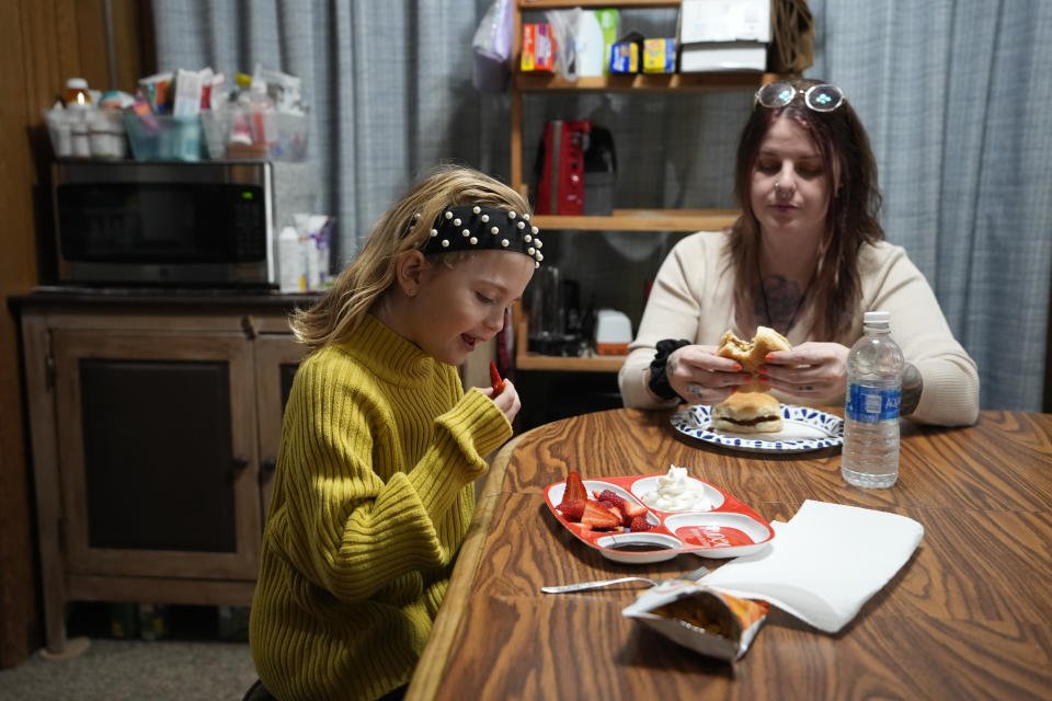 Eight-year-old Estella Baraniak has a snack with her mother Ashley Snyder in Halifax, Pa., Wednesday, March 6, 2024. Across the country, it's not uncommon for the relatives of prisoners who died on the job to struggle with determining who's liable. When workers' compensation is offered, the amount awarded is typically determined by the size of the worker's paycheck and usually closes the door on future wrongful death suits. (AP Photo/Matt Rourke)