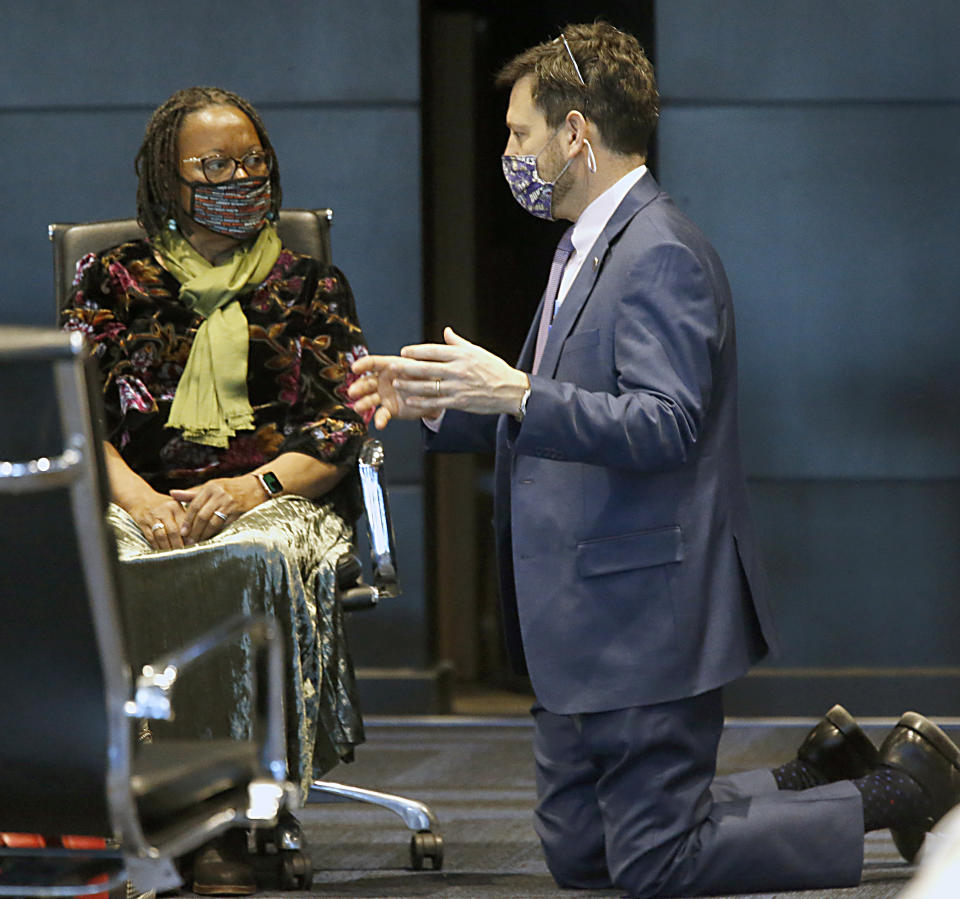 Sen. Scott Surovell, D-Fairfax, right, gets on his knees for a conversation with Sen. Mamie Locke, D-Hampton, who is chair of the Senate Democratic caucus, during the floor session of the Virginia Senate inside the Science Museum in Richmond, Va Thursday, Jan. 28, 2021. Surovell was talking with many of the members as the Senate met, trying to gain support for SB1165, his legislation eliminating the death penalty. He asked that the bill be brought up tomorrow. (Bob Brown/Richmond Times-Dispatch via AP)