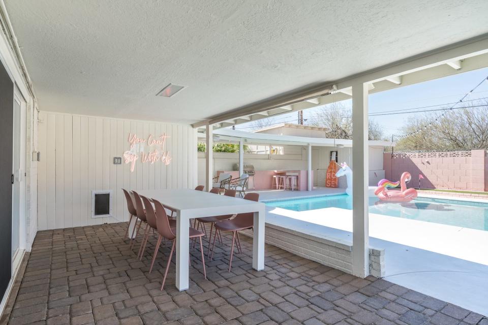 A patio with pink chairs overlooking a pool.