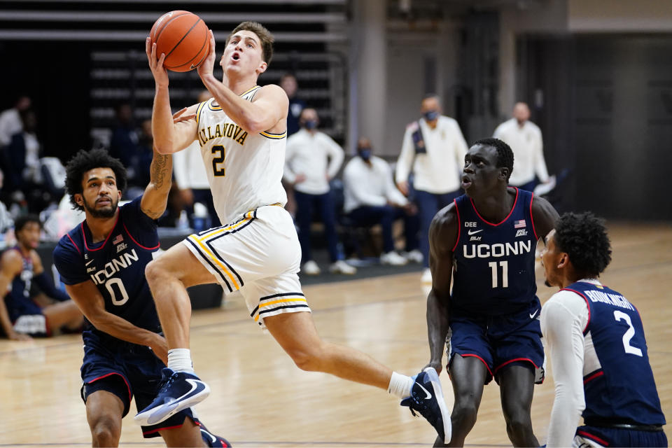 FILE - Villanova's Collin Gillespie (2) goes up for a shot against Connecticut's Jalen Gaffney (0), Akok Akok (11) and James Bouknight (2) during the first half of an NCAA college basketball game in Villanova, Pa., in this Saturday, Feb. 20, 2021, file photo. Villanova's Collin Gillespie was selected to The Associated Press preseason All-America NCAA college basketball team, announced Monday, Oct. 25, 2021. (AP Photo/Matt Slocum, File)