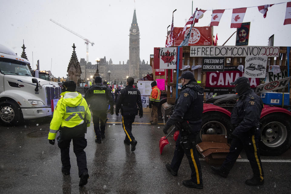 Police walk through parked trucks to make an arrest on Wellington Street, during an ongoing protest against COVID-19 measures that has grown into a broader anti-government protest, in Ottawa, Ontario, on Thursday, Feb. 17, 2022. (Justin Tang/The Canadian Press via AP)