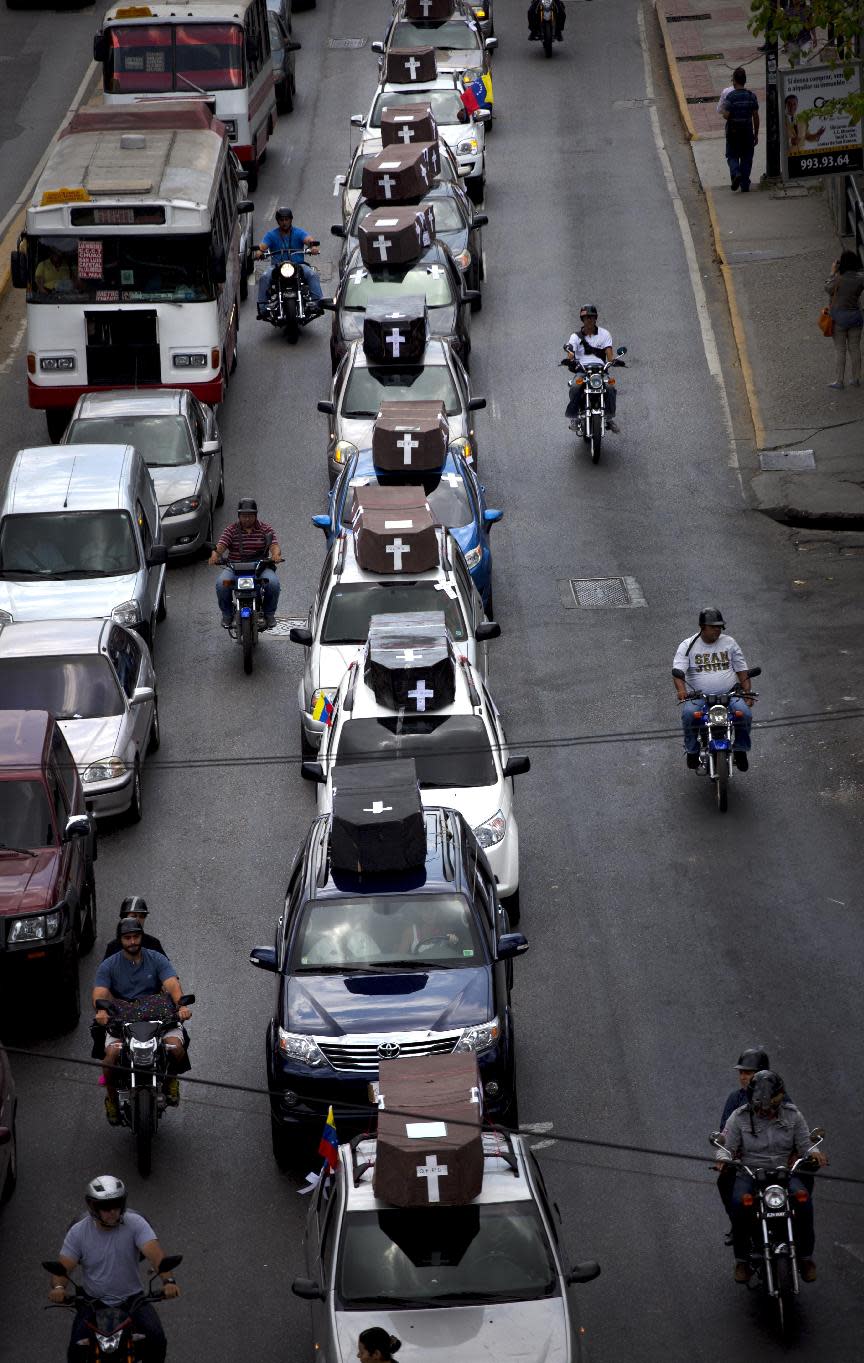 Una hilera de vehículos con ataúdes de cartón recorre las calles de Caracas durante una manifestación en honor a los caídos durante las protestas en Venezuela, el martes 15 de abril de 2014. (Foto AP/Ramón Espinosa)