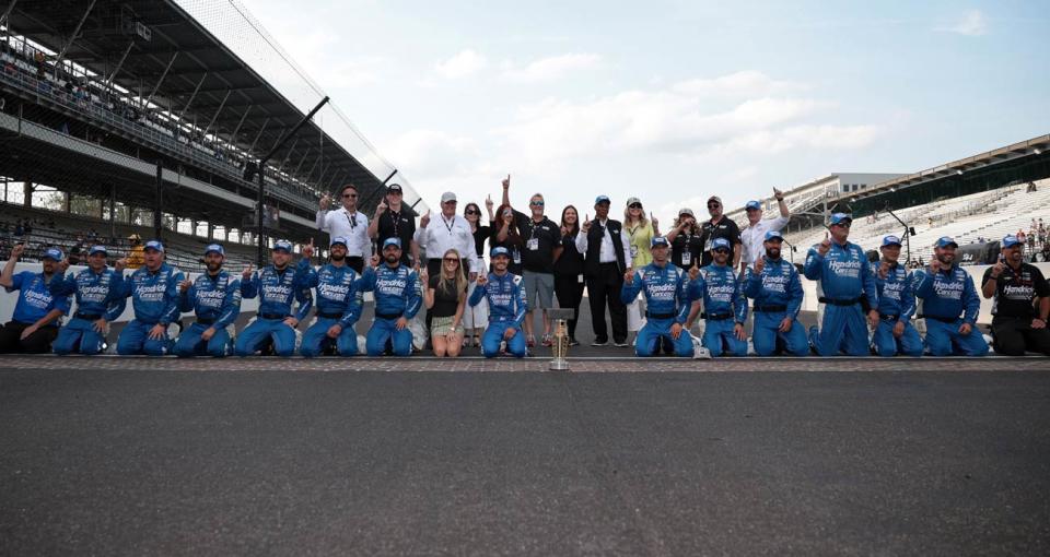 Kyle Larson y su equipo de boxes No. 5 de Hendrick Motorsports posan para una foto en la línea de salida/llegada en el Indianapolis Motor Speedway.