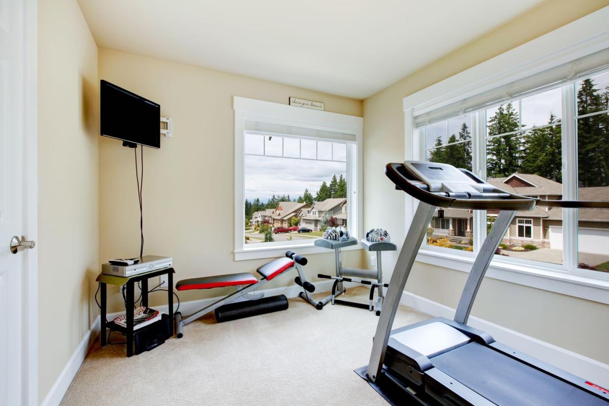 home gym with equipment, weights and TV with two large windows