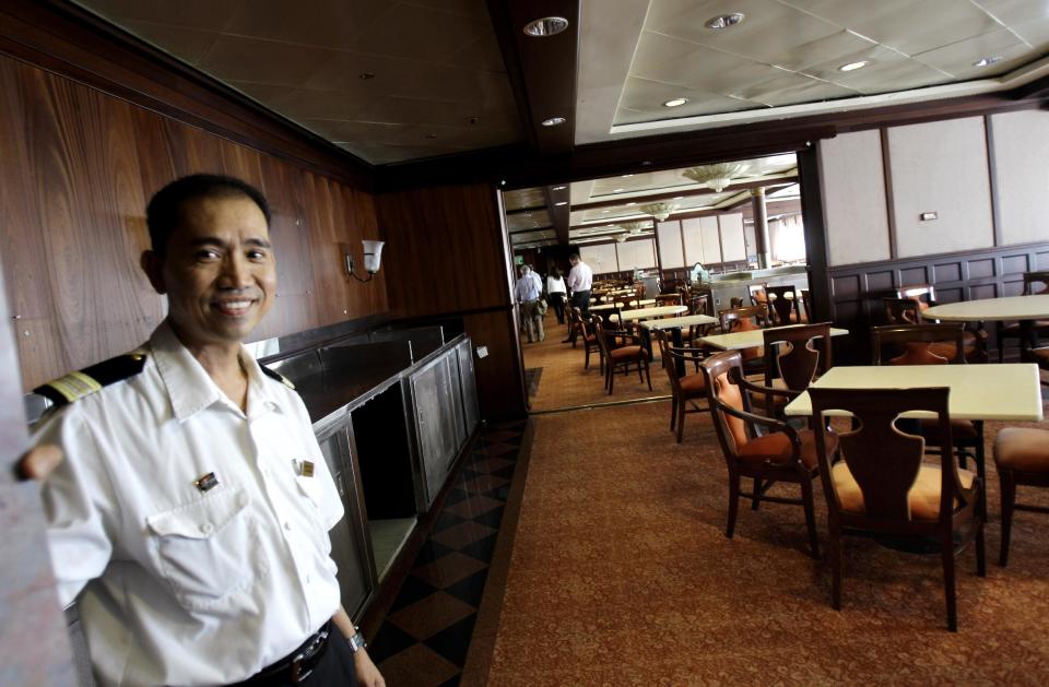 FILE - In this Monday, July 2, 2012 file photo, Chief steward, Ronald Gelmo, welcomes visitors to the Queen Elizabeth 2 as Istithmar World, the Dubai state investment company that owns the ship, outlined plans Monday to turn the retired cruise liner into a 300-room hotel, ending years of speculation about its fate, in Port Rashid, Dubai, United Arab Emirates. The Dubai owners of the storied passenger liner Queen Elizabeth 2 say the ship will be moved to Asia as a floating luxury hotel. (AP Photo/Kamran Jebreili)