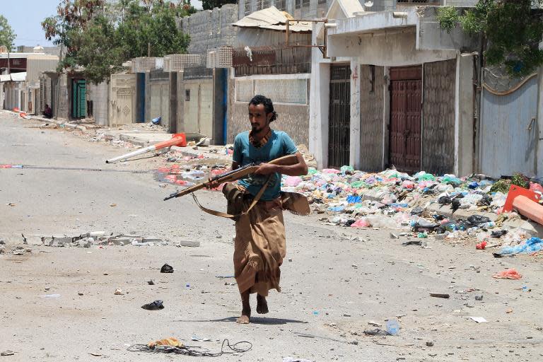 An armed militiaman loyal to Yemen's fugitive President Abderabbo Mansour Hadi carries a rifle as he walks in a street during reported clashes with Huthi rebels in the port city of Aden's Dar Saad suburb, on April 24, 2015