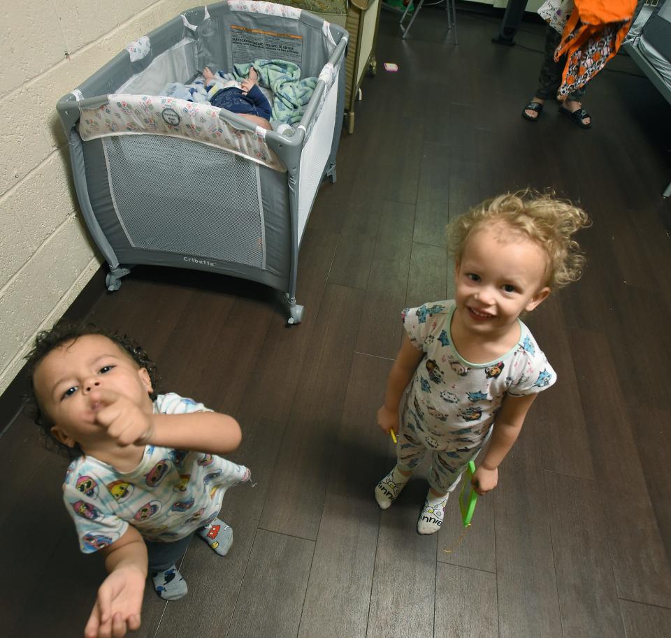 Daylen Daykin, 2, and his sister Violet, 3, wanted to have their picture taken while their mom, Romy Kelley, made the beds at the Oaks Shelter in Monroe. Their three-month-old brother Rylo laid in his pack and play portable crib.