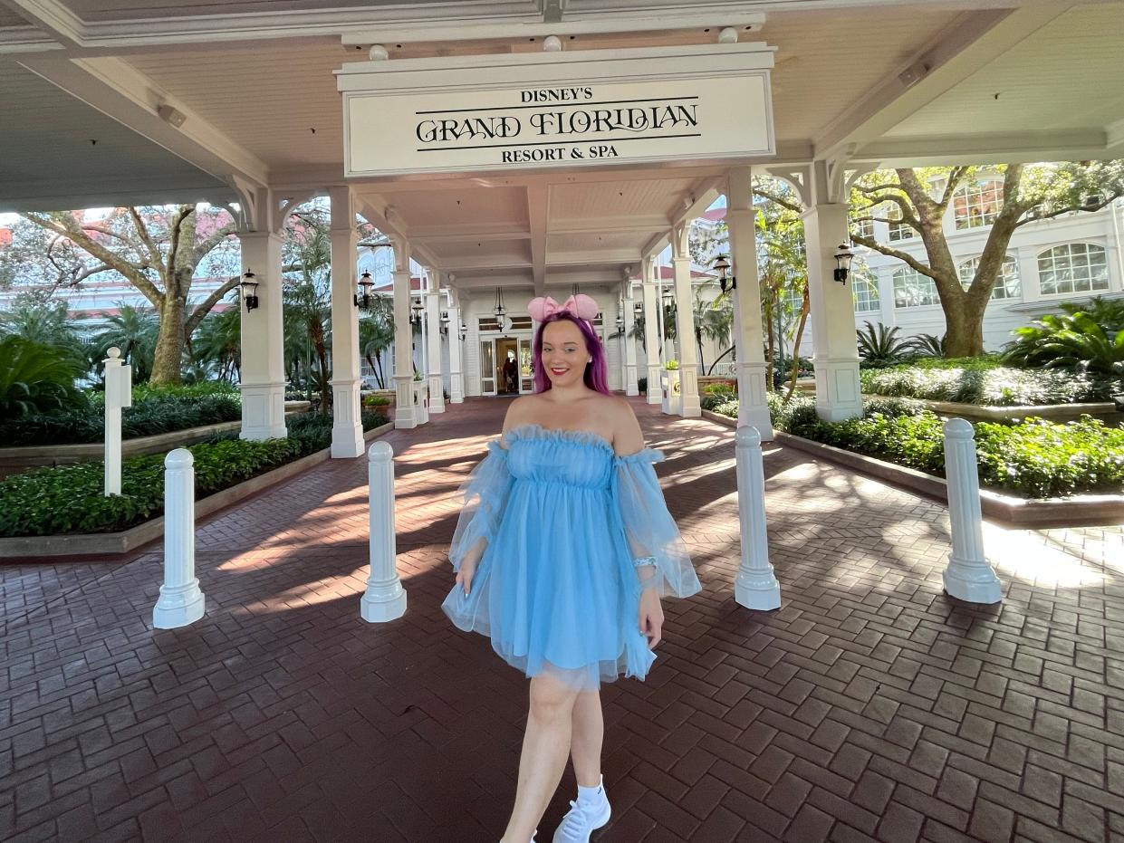 jenna posing for a photo under the sign for disney's grand floridian resort at the main entrance