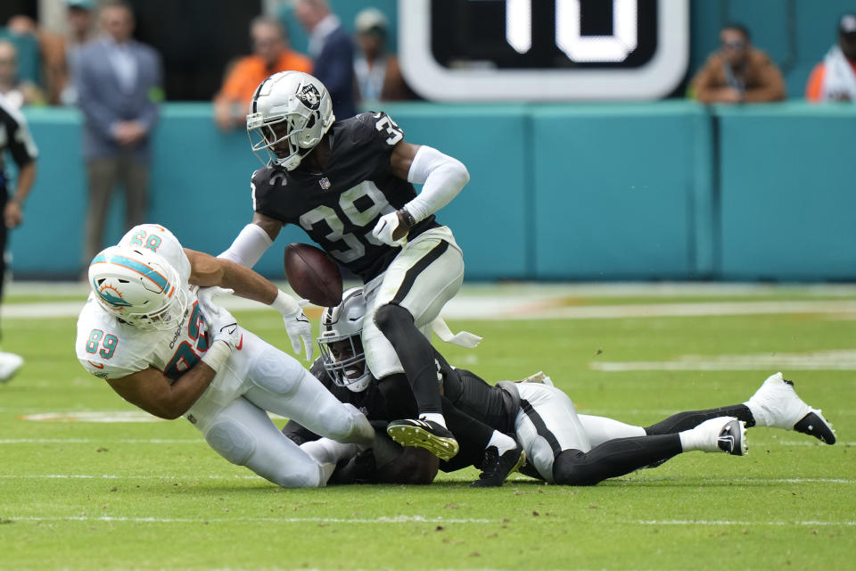 Miami Dolphins tight end Julian Hill (89) fumbles the ball under pressure from Las Vegas Raiders cornerback Nate Hobbs (39) and Divine Deablo during the first half of an NFL football game, Sunday, Nov. 19, 2023, in Miami Gardens, Fla. (AP Photo/Wilfredo Lee)