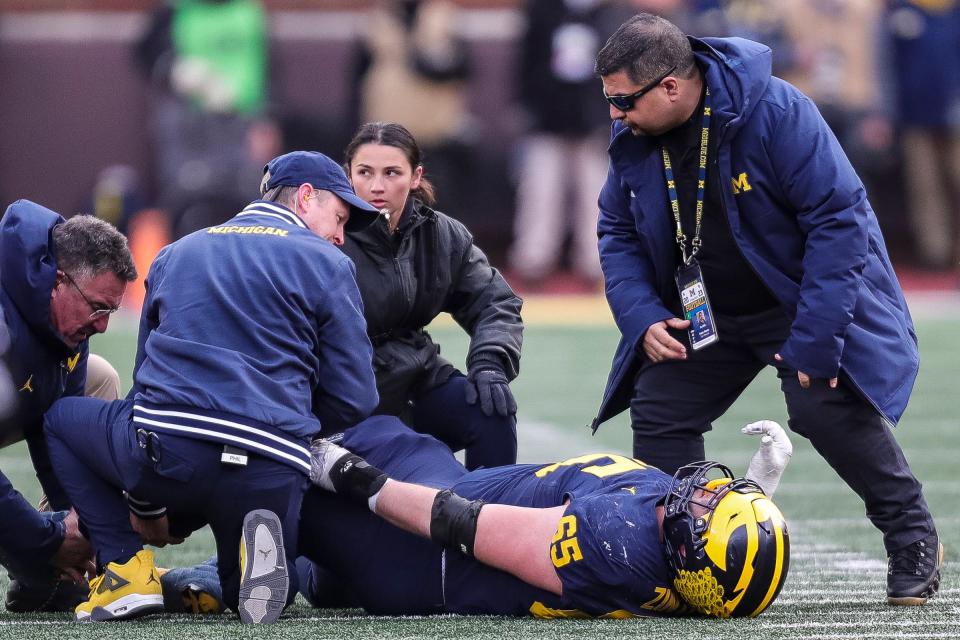 Michigan football staff checks on the injury to offensive lineman Zak Zinter during the second half against Ohio State at Michigan Stadium in Ann Arbor on Saturday, Nov. 25, 2023.