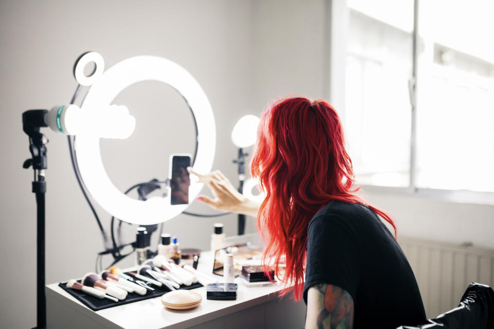 A person using a ring light and phone at a makeup vanity