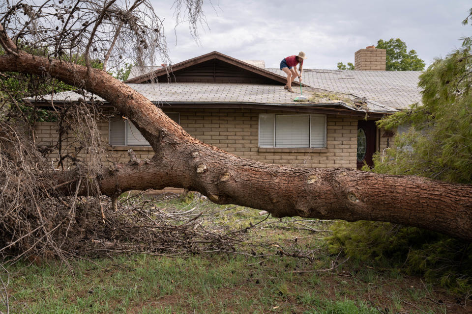 Cassandra Steeno clears debris off the roof of her father's home on Melody Lane in Gilbert on July 14, 2022.